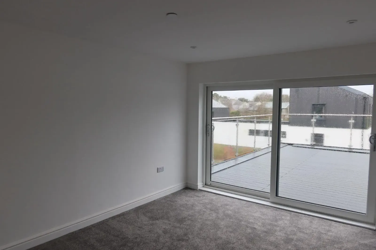 A newly finished room with pristine white plastered walls and grey carpet, showcasing the high-quality finish after internal wall insulation by Global Energy Insulation in South Wales.