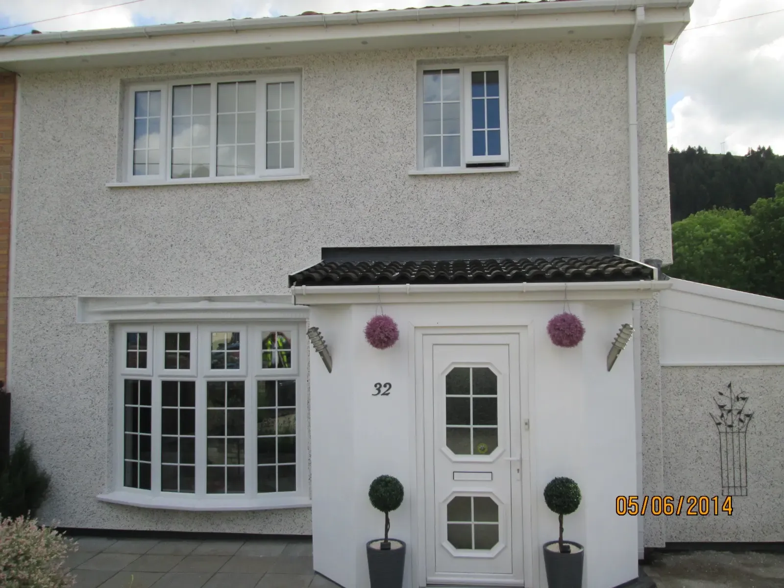 A white semi-detached house with external wall insulation and rendering