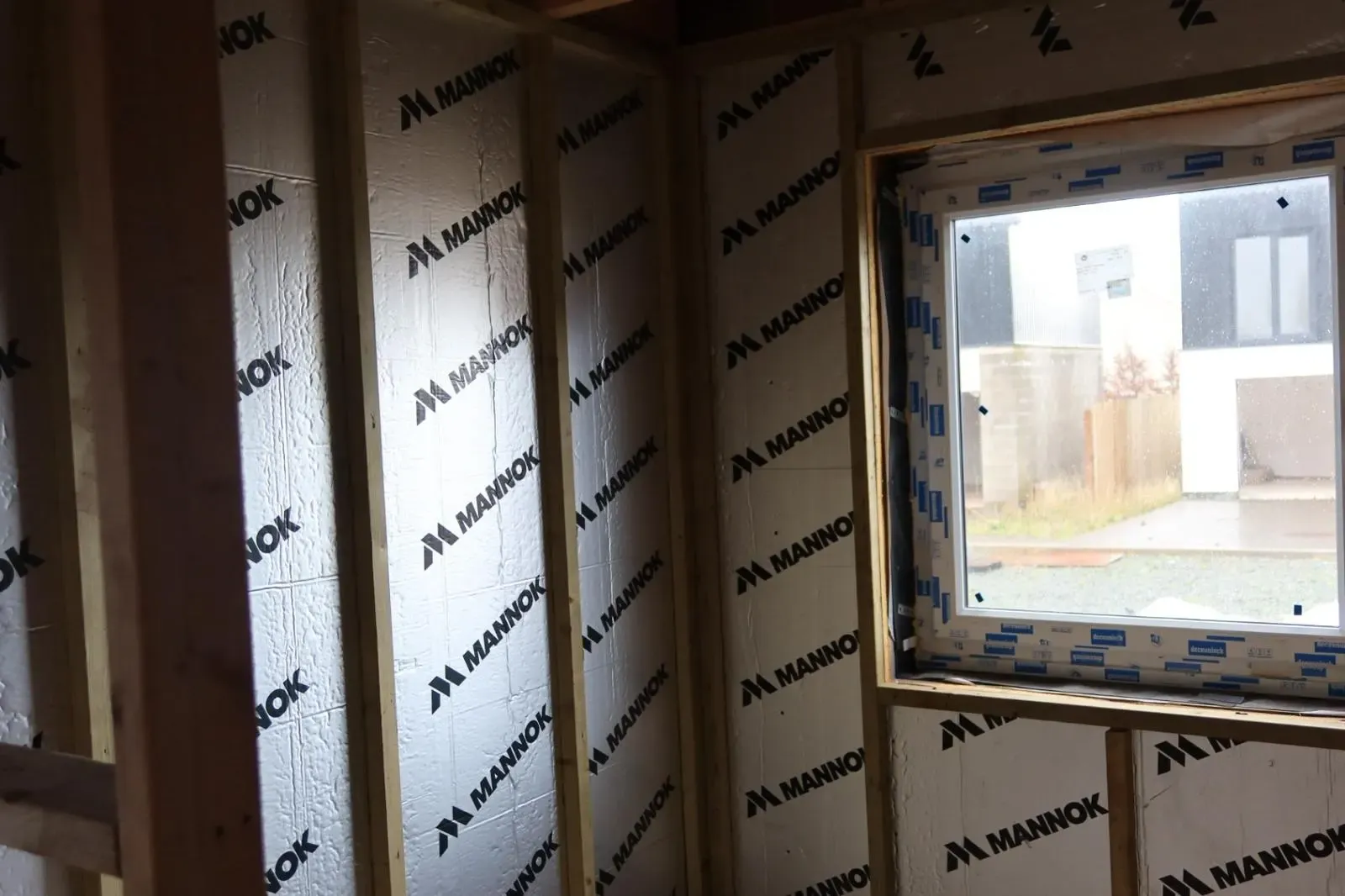 Internal wall insulation installation featuring rigid foil boards fitted between timber studs to reduce heat loss.